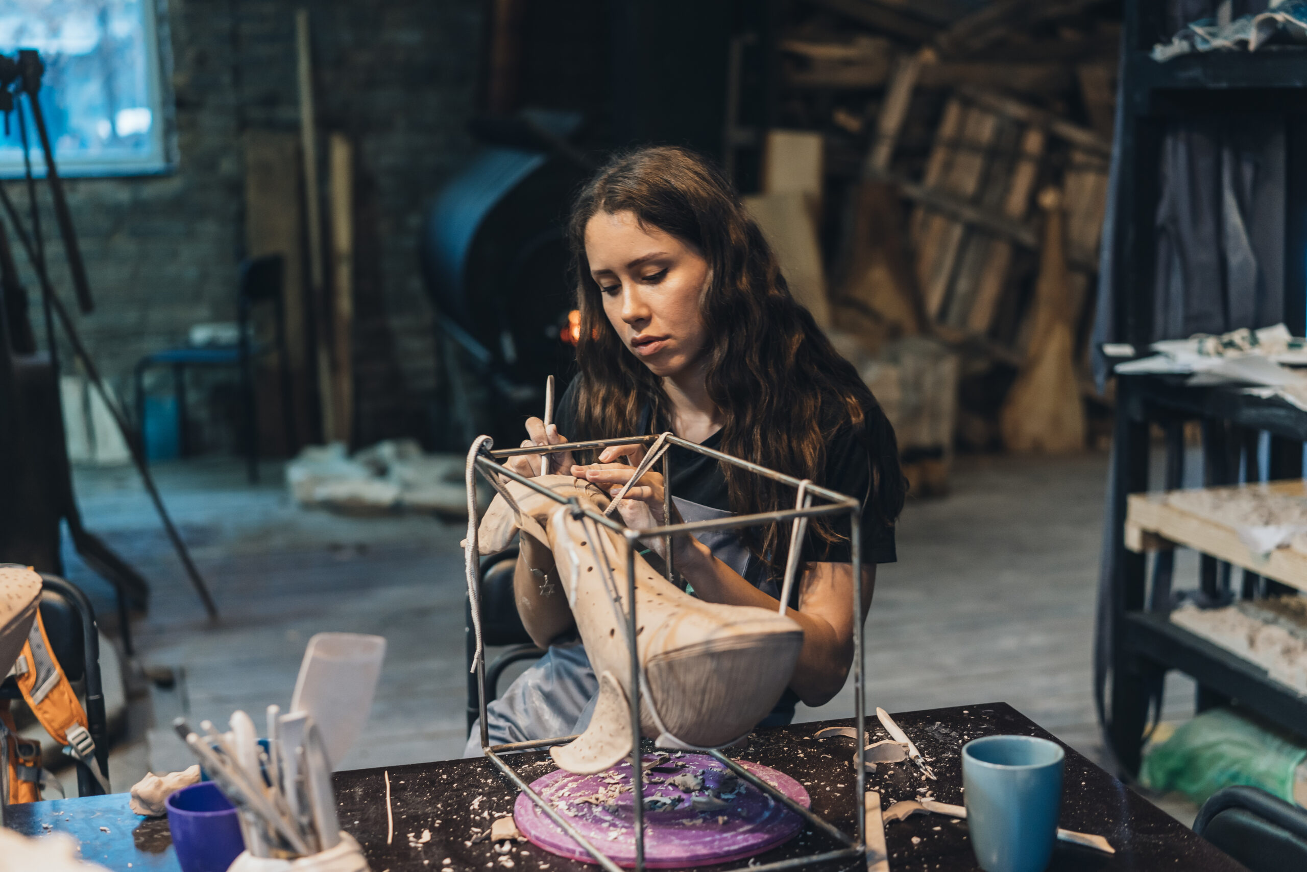 Portrait of young woman enjoying favorite job in workshop. The potter carefully works on the clay whale